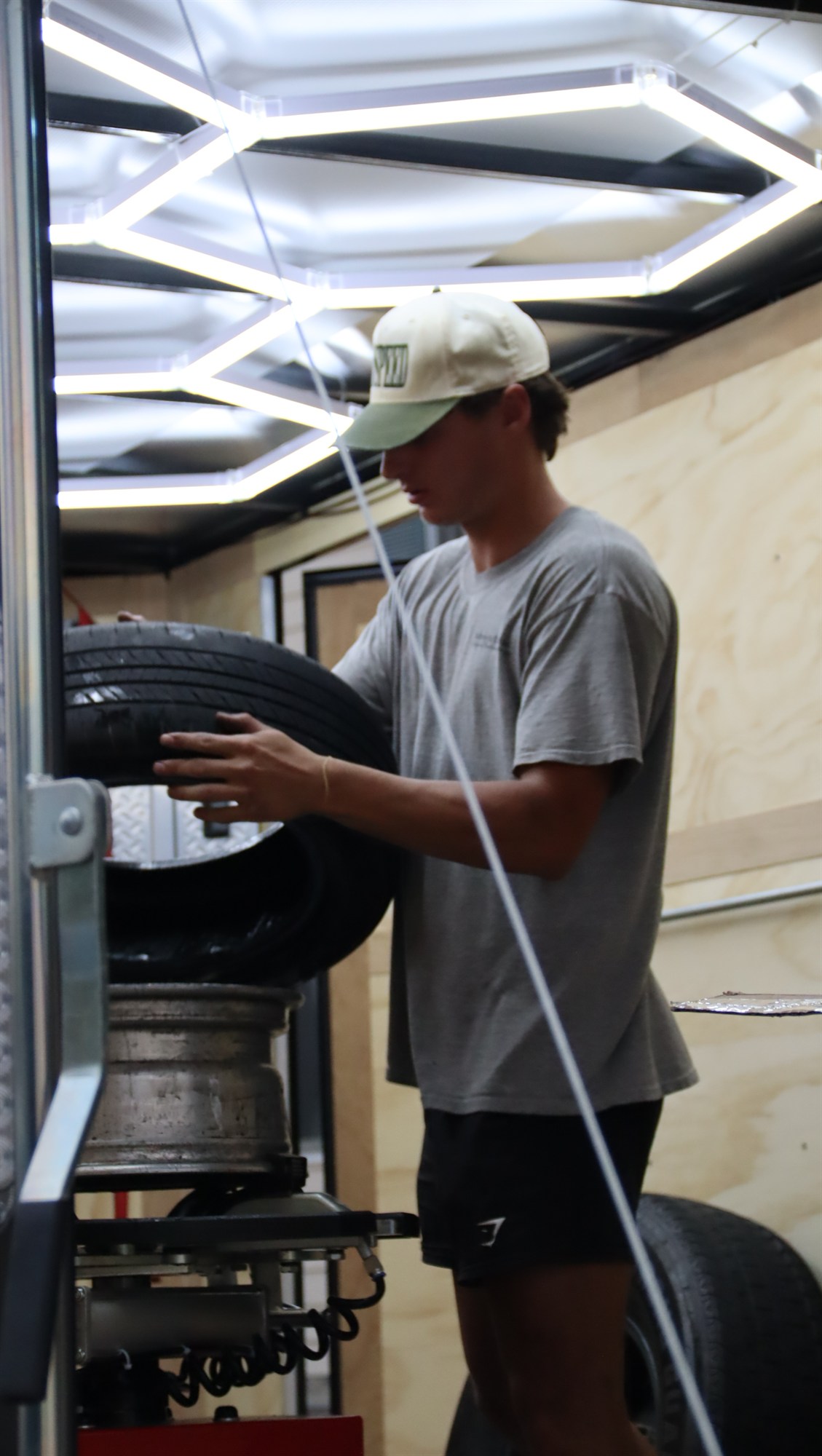 Dylan mounting a tire on the balancer inside the RollOut mobile service trailer